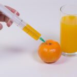 cropped-image-woman-hand-injecting-orange-fruit-against-white-background_1048944-8399679