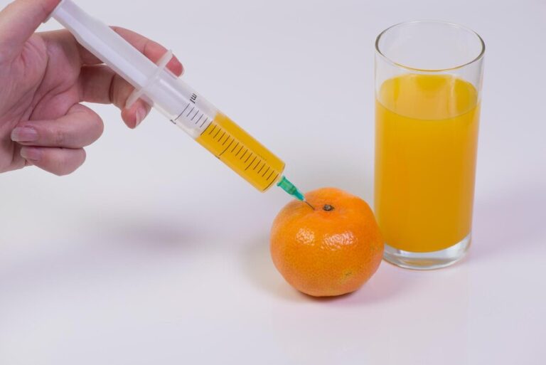 cropped-image-woman-hand-injecting-orange-fruit-against-white-background_1048944-8399679