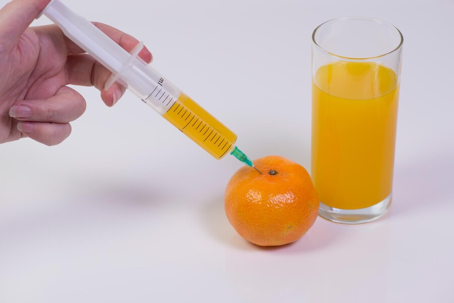 cropped-image-woman-hand-injecting-orange-fruit-against-white-background_1048944-8399679