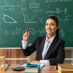impressed-young-female-teacher-sits-table-with-school-tools-raising-pen-classroom_141793-106366
