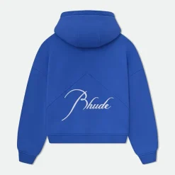 n the rapidly evolving world of fashion, few brands have disrupted the industry as boldly as Rhude Clothing. What started as a graphic tee worn by Kendrick Lamar has grown into a globally recognized luxury streetwear label, blending high-end craftsmanship with raw, cultural storytelling. Founded in 2015, Rhude has become a staple in the wardrobes of celebrities, athletes, and tastemakers. With its signature fusion of American nostalgia, minimalist design, and edgy aesthetics, Rhude Clothing reflects a new chapter in streetwear—where personal narrative meets designer-grade quality. In this deep dive, we’ll explore the origins of Rhude Clothing, what makes the brand so unique, its signature pieces, game-changing collaborations, and where it’s headed next in the world of fashion. The Origin Story of Rhude Clothing The story of Rhude begins with its founder, Rhuigi Villaseñor, a self-taught designer who immigrated from the Philippines to Los Angeles at age 11. With no formal fashion education, Rhuigi learned everything from YouTube tutorials, working with tailors, and deconstructing clothes to understand how they were made. His approach was hands-on, raw, and incredibly passionate. In 2015, he launched Rhude Clothing with a single design: a T-shirt featuring a paisley bandana print. It was a simple idea, rooted in symbolism and street culture—but it caught fire quickly. When Kendrick Lamar wore it during a public appearance, the fashion world took notice. Rhuigi’s background heavily influences the Rhude brand ethos—blending his immigrant experience, love of Americana, and aspirational storytelling into every piece. Rhude isn’t just about clothes; it’s about identity, ambition, and cultural connection. Why Rhude Clothing Stands Out In a sea of emerging streetwear brands, Rhude Clothing has managed to rise above the rest. Its success isn't based on hype alone—it's built on a careful combination of authenticity, luxury, and storytelling. Here’s what makes Rhude so unique: 1. Luxury-Grade Craftsmanship Unlike many streetwear brands that focus purely on graphic tees and hoodies, Rhude takes a more refined approach. The brand emphasizes tailoring, fit, and quality—with many of its garments produced in Italy or the United States. From double-stitched hems to heavyweight cotton and premium zippers, Rhude pieces are designed to last and feel luxurious. 2. Cultural Storytelling Rhude Clothing is deeply personal. Each collection is inspired by Rhuigi’s life—his childhood in Manila, his upbringing in LA, and his perspective as an immigrant in America. Themes like the American Dream, racial identity, and vintage nostalgia are often embedded in the garments. These aren’t just clothes—they’re conversation starters. 3. Distinctive Aesthetic Rhude has a clear visual identity: bold yet minimal, vintage but polished. Think race car jackets, pleated trousers, oversized flannels, and luxe logo tees. You’ll often find classic motifs (like bandanas, flags, or retro fonts) paired with modern cuts and luxe fabrications. It’s a brand where California cool meets European edge. Key Pieces That Define Rhude Clothing Rhude has developed several signature items that have become iconic in streetwear and luxury fashion circles: Cigarette Track Pants: These relaxed-fit pants feature contrast piping and a cigarette-style stripe down the side. They're sporty, sleek, and highly sought after. Bandana Print Shirts and Tees: A nod to the brand’s first viral product, these pieces pay homage to West Coast street culture while offering elevated design. Motorsport-Inspired Jackets: Rhude’s racing jackets channel 90s F1 aesthetics and NASCAR influences, combining bold sponsor graphics with clean silhouettes. Logo Hoodies and Tees: Subtle yet powerful branding is a Rhude trademark. Even basic items are elevated through construction and detailing. Pleated Trousers: These trousers reflect Rhude’s shift toward a more tailored, grown-up approach to streetwear—perfect for casual wear or elevated occasions. Celebrity Endorsement and Cultural Influence One of the biggest accelerators for Rhude Clothing has been its massive celebrity backing. The brand has been seen on: Jay-Z LeBron James Kendrick Lamar Justin Bieber A$AP Rocky Kevin Durant Michael B. Jordan Odell Beckham Jr. These cultural icons don’t just wear Rhude—they embody its values: ambition, excellence, and individuality. The organic celebrity support has helped Rhude transcend traditional fashion marketing, putting it directly into the spotlight of music, sports, and entertainment. Game-Changing Collaborations Rhude’s strategic collaborations have helped solidify its position as a dynamic, forward-thinking brand. Some notable partnerships include: Rhude x Puma This collab combined retro sportswear with Rhude’s signature aesthetic. The footwear featured chunky silhouettes, suede finishes, and motorsport influences, while the apparel blended athletic wear with street-ready fits. Rhude x McLaren As part of a limited-edition motorsport-inspired collection, Rhude teamed up with McLaren Racing to create jackets, tees, and accessories that celebrated speed, precision, and power. Rhude x Thierry Lasry This eyewear collaboration brought together Rhude’s street credibility with Lasry’s Parisian luxury, resulting in a premium collection of sunglasses that were equal parts style and statement. Each partnership has allowed Rhude to expand its reach, tap into new audiences, and explore different creative territories—all without losing its unique brand identity. Rhude on the Runway In 2020, Rhude made its debut at Paris Fashion Week, a significant milestone that elevated the brand from streetwear to serious high fashion. The collection revealed a more tailored, mature direction—incorporating suits, coats, and refined layering. This move signaled Rhude’s ambitions beyond hype and drop culture. Rhuigi has made it clear: he’s not just designing clothes, he’s building a luxury fashion house. Where to Buy Rhude Clothing Due to its popularity and limited production runs, Rhude Clothing is considered a high-demand label. You can purchase Rhude pieces through: Rhude's official website SSENSE Farfetch MR PORTER KITH Saks Fifth Avenue Dover Street Market Be aware that new drops sell out fast. Collectors and fashion fans often track Rhude releases like sneaker launches—because once it’s gone, it’s gone. The Future of Rhude Clothing Rhude is showing no signs of slowing down. In 2022, Rhuigi Villaseñor was appointed Creative Director of Bally, the Swiss luxury brand, further solidifying his place in the elite design world. His work at Bally and his continued innovation with Rhude prove that he's one of the most versatile and influential designers of his generation. Looking ahead, we can expect Rhude to evolve even further—with more high-fashion shows, expanded product lines, and deeper integration into lifestyle markets, including fragrance, accessories, and even furniture. Final Thoughts: Why Rhude Clothing Matters Rhude Clothing isn’t just a fashion brand—it’s a cultural statement. It speaks to a new generation that wants more from its clothes: quality, authenticity, and meaning. With its roots in immigrant identity, American heritage, and high-fashion ambition, Rhude has created a blueprint for the future of luxury streetwear. Whether you're a fashion enthusiast, a streetwear collector, or simply someone who appreciates bold yet thoughtful design, Rhude Clothing is worth the investment. It's not just about looking good—it's about wearing a story.
