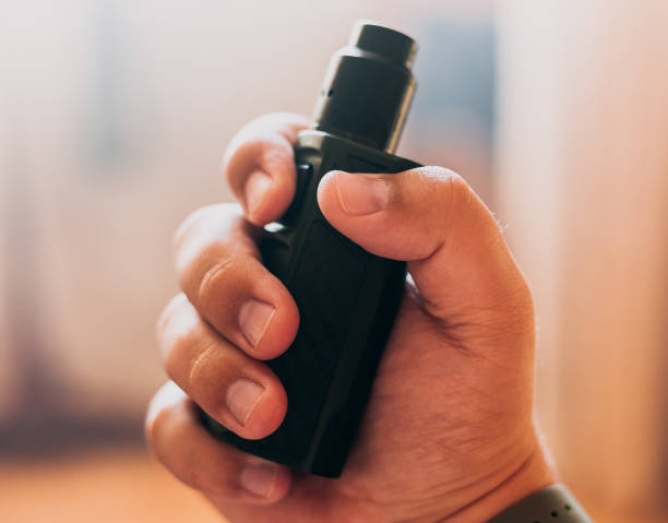 Vape device in mans hand, selective focus
