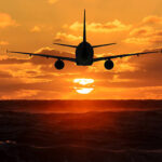 Airplane in the sky is flying into the sunset over the sea 3D rendering