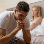 man sitting on the bed with woman on the back