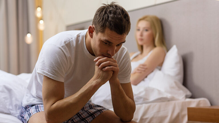 man sitting on the bed with woman on the back
