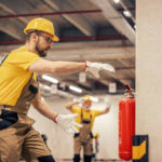 Young man using fire extinguisher in warehouse.Fire extinguishers.