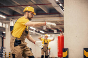 Young man using fire extinguisher in warehouse.Fire extinguishers.