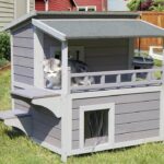 A cat sits atop a heated outdoor cat house, showcasing a cozy and inviting space for feline relaxation.