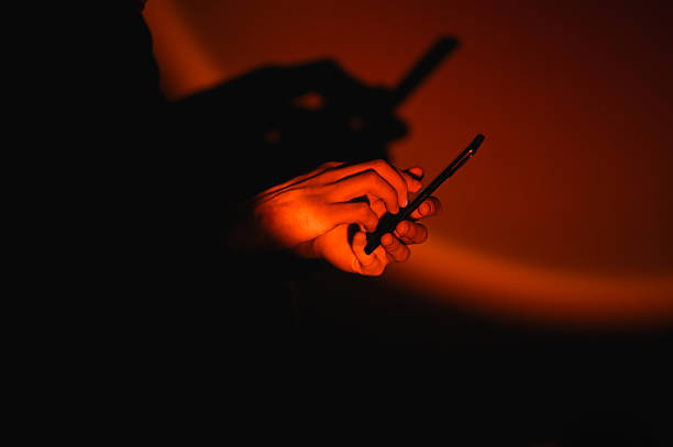 Person using smartphone in the dark with dramatic red lighting
