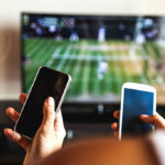 Friends using mobile phone during a tennis match on the TV.