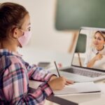 schoolgirl-writing-while-having-online-class-with-her-teacher-laptop-due-virus-pandemic_637285-9416