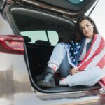brunette-woman-wearing-big-usa-flag-car-trunk