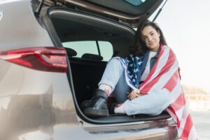 brunette-woman-wearing-big-usa-flag-car-trunk