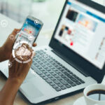 A professional using a smartphone and laptop connected to cloud graphics to improve B2B website conversion.