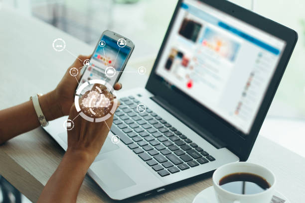 A professional using a smartphone and laptop connected to cloud graphics to improve B2B website conversion.